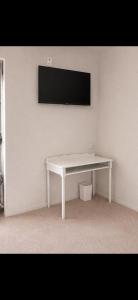 a white desk with a tv on a white wall at La Canopée in La Gouesnière