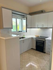 a kitchen with white cabinets and a black stove at Dimitris House in Pllakë +13 photos