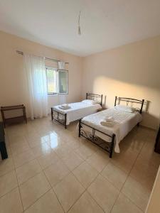 two beds in a room with a tiled floor at Dimitris House in Pllakë