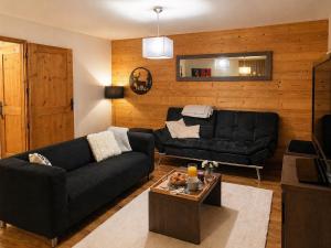 a living room with a black couch and a table at Résidence Clos St-Hilaire 88m2 - Terrasse 12m2 in Saint-Lary-Soulan
