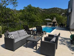 a patio with a couch and chairs next to a pool at Apartment Ćulum in Peračko Blato