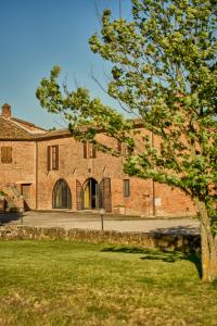 a large brick building with a door in a yard at Podere il Granaio - Crete Senesi - Tuscany in Siena