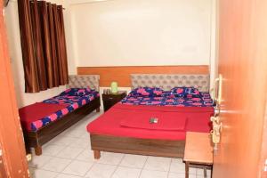 a bedroom with two beds with red and blue sheets at SAIRATNA HOTEL only 1 minute distance from sai temple in Shirdi