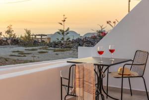 a table with two glasses of wine on a balcony at Theophrasti Suites in Foinikiá