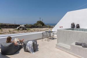 a woman sitting on a couch reading a book on a roof at Theophrasti Suites in Foinikiá