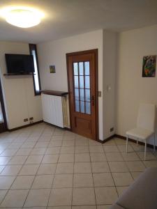 ein Wohnzimmer mit Tür und Fliesenboden in der Unterkunft CA d'ADUA in Pray