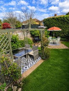a patio with a table and an umbrella in a yard at Rossetti Retreat in Birchington