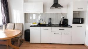 a kitchen with white cabinets and a sink and a table at Apollo Home - Im Zentrum der Natur in Wildflecken