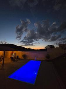 a blue swimming pool with a sunset in the background at Pousada real chalés in Belo Vale