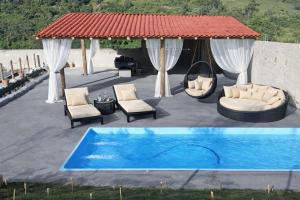 a patio with a gazebo and a blue pool at Pousada real chalés in Belo Vale