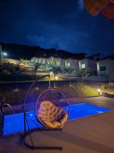 a chair sitting on top of a pool at night at Pousada real chalés in Belo Vale