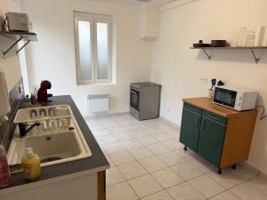 a kitchen with a sink and a microwave at Maisonnette du Prieuré in Saint-Gilles