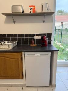 a kitchen with a black counter and a white dishwasher at Maisonnette du Prieuré in Saint-Gilles