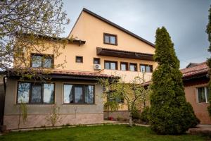 a house with a tree in front of it at Pensiunea Vis Braila in Vărsătura