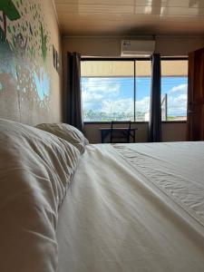 a bedroom with a white bed with a large window at Aracari Stay in Quepos +10 photos