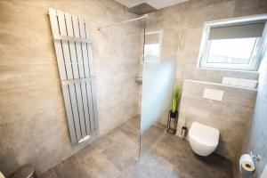 a bathroom with a toilet and a glass shower at Lakeside Diamond Apartment - Krumpendorf in Krumpendorf am Wörthersee +17 photos