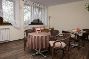 a room with a table and chairs and windows at Pensiunea Vis Braila in Vărsătura