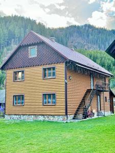 a large wooden house with a staircase in front of it at Садиба у Софійки in Synevyrsʼka Polyana