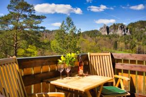a wooden table with two glasses of wine on a balcony at Ferienwohnung Villa Oben im Sandsteinidyll in Rathen