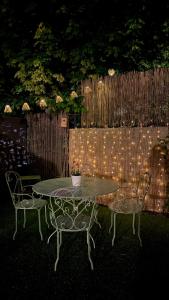 a table and two chairs and a fence with lights at CHEZ LOU - Grand espace cosy 60 m2 entrée indépendante dans maison privée au calme in Bucey-lès-Gy +62 photos