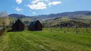two barns in a field with mountains in the background at Rest&peace homes in Mojkovac