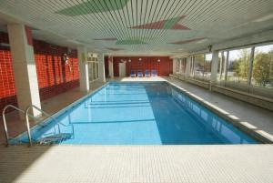 a large swimming pool with blue water in a building at Helle FeWo am Waldrand - mit Balkon, Pool, Sauna & Freizeitgelände in Freyung
