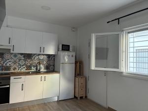 a kitchen with white cabinets and a white refrigerator at Nuestro lugar feliz Apartamento Barbate - Patio ducha exterior in Barbate