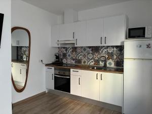a kitchen with white cabinets and a sink and a mirror at Nuestro lugar feliz Apartamento Barbate - Patio ducha exterior in Barbate
