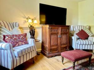 a living room with two chairs and a tv at Manor Cottage in Cavendish