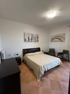 a bedroom with a bed and two chairs and a table at Il Quinto senso di Lù in Capalbio