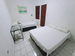 a bedroom with two beds and a glass table at Pousada Maria Bonita - Centro, 10min da Praia de Camapum, Macau RN in Macau