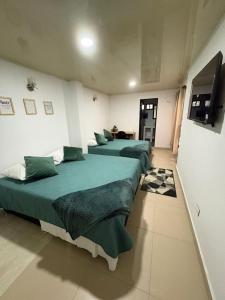 a room with three beds with green sheets and a tv at Edificio La Roca in Pereira