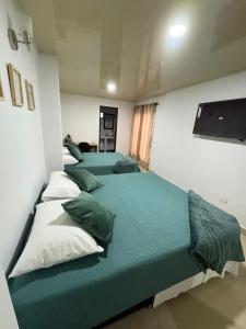 three beds in a room with green sheets and pillows at Edificio La Roca in Pereira +12 photos