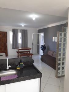 a kitchen and living room with a black counter top at Apartamento 204 com vista da piscina e mar in Piúma