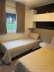 two beds in a small room with a window at Mobil Home La Barrosa in Chiclana de la Frontera