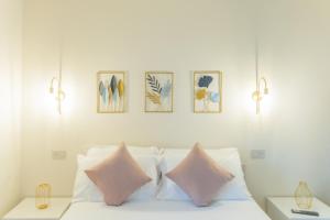 a white bed with pink pillows and pictures on the wall at Agriturismo Podere Sant' Agnese - Suite Apartment in Bibbiena