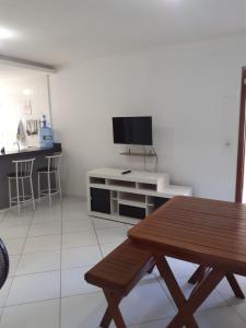 a living room with a table and a flat screen tv at Apartamento 204 com vista da piscina e mar in Piúma