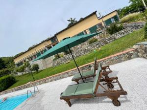 a lounge chair with an umbrella next to a pool at Residence The Cherry House - Appartamenti con piscina in Carro