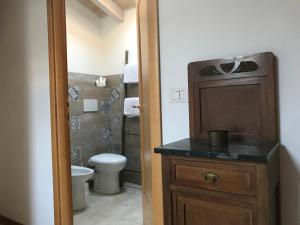 a bathroom with a toilet and a wooden cabinet with a sink at Residence The Cherry House - Appartamenti con piscina in Carro