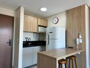 a kitchen with a white refrigerator and wooden cabinets at Apartamento 83 - Carmelo in Ribeirão Preto