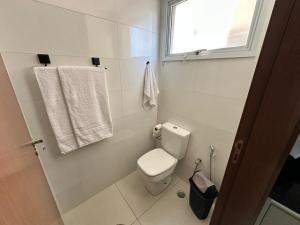 a bathroom with a toilet and a window and towels at Apartamento 83 - Carmelo in Ribeirão Preto +12 photos