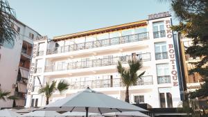 a white building with umbrellas in front of it at Hotel Ruko Boutique Deluxe in Golem