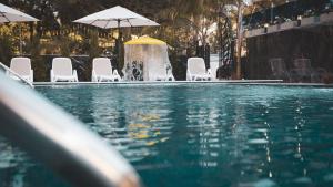 a pool with chairs and a fountain with umbrellas at Hotel Ruko Boutique Deluxe in Golem