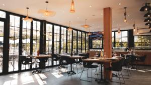 a restaurant with tables and chairs and large windows at Hotel Ruko Boutique Deluxe in Golem