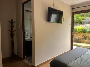 a bedroom with a bed and a television on the wall at Posada Tierra Viva - Villa de Leyva in Villa de Leyva