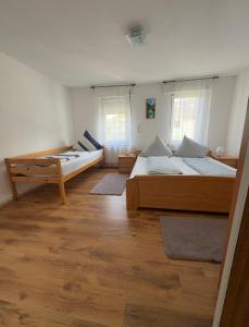 two beds in a room with wooden floors and windows at Dürschgangs Zimmer in Siegen