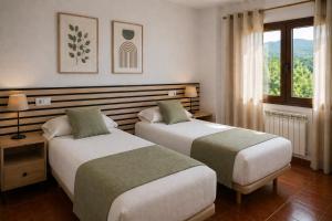 a hotel room with two beds and a window at L'Albea Hotel Rural in Vall dʼAlba