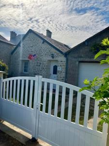 a white fence in front of a house at Abri 82 in Picauville