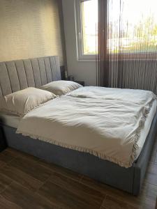 a bed with white sheets and a window in a room at Nice Wellness Apartman in Siófok