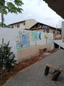 a wall with a painting on it next to a bench at hospedagem da rosa in Morretes